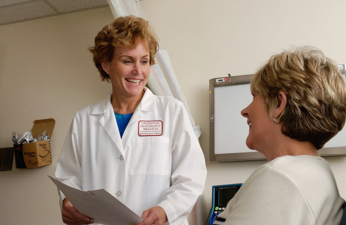 A clinician holding paperwork while speaking with a patient, in a National Cancer Institute photograph